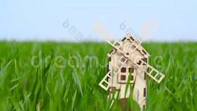 农业和农业。 一个用木头做的小装饰磨坊矗立在麦田的绿草中。 概念